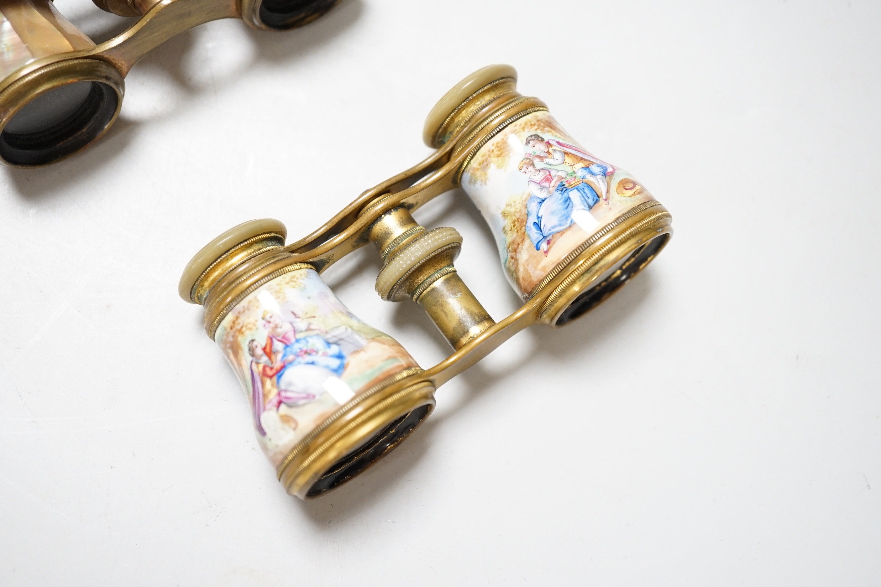 A pair of gilt brass and enamelled opera glasses and a similar pair of mother-of-pearl veneered opera glasses